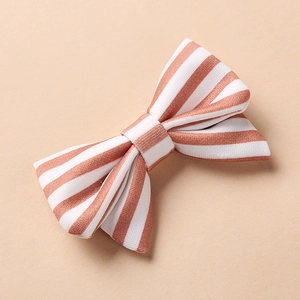 Détail de la pince à cheveux pour enfants avec motif à rayures orange et texture tissu