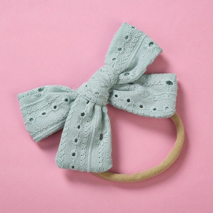Detailed view of mint green cotton lace bow with embroidery on soft nylon headband