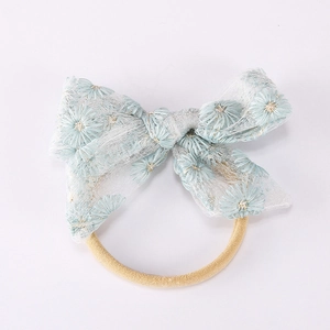 Détail du bandeau bébé avec nœud en dentelle et broderie marguerites sur tulle bleu clair