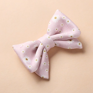 Détail de la barrette à nœud en tissu rose avec motif floral marguerite pour bébé