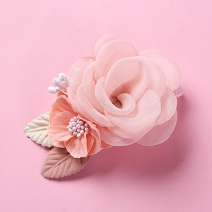 Close-up of pink fabric flower hair clip with translucent petals and delicate berries