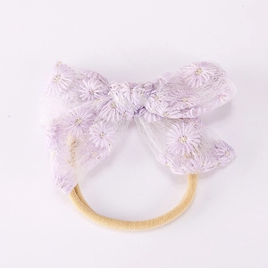 Détail du nœud en dentelle violette brodé de marguerites et bandeau pour bébé