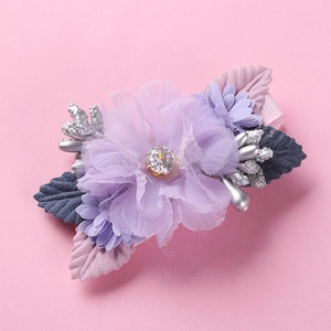 Close-up of handmade purple tulle flower hair clip with pearl and leaf detail