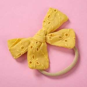 Detailed macro view of yellow cotton lace bow headband with floral embroidery