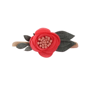 Detailed macro shot of red felt flower and green leaves on soft beige nylon baby headband