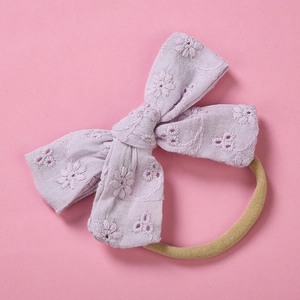 Close-up of purple cotton bow with floral embroidery on a soft nylon baby headband