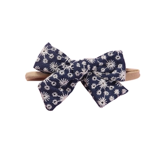 Set of 10 soft nylon baby headbands with navy floral embroidered bow on white background