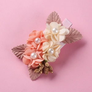 Detailed view of handmade pink fabric flower hair clip with pearl centers and gold accents