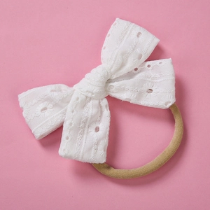 Detail view of white embroidered cotton lace bow on soft nylon elastic baby headband