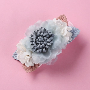 Detailed close-up of light blue fabric flower hair clip with pearls and lace on pink background