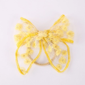 Vue détaillée de la broderie marguerite sur le bandeau bébé en maille jaune à nœud