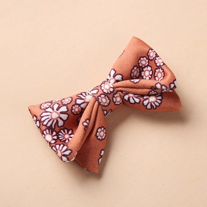 Détail de la texture d'une pince à cheveux bébé avec motif marguerite orange et nœud
