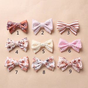 Vue à plat de neuf barrettes à nœuds en tissu fleuri et à pois aux tons pastel doux
