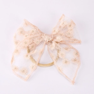Gros plan d'un bandeau en dentelle champagne avec broderie marguerite et tulle doux