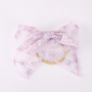 Détail de l'élastique en dentelle rose avec nœud brodé de petites marguerites blanches
