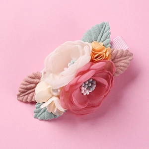 Detailed close-up of pink and beige fabric flower hair clip with pearl center and velvet leaves