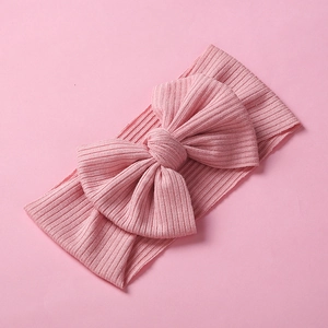 Dettaglio della fascia elastica in maglia a coste per neonati con un grande fiocco rosa