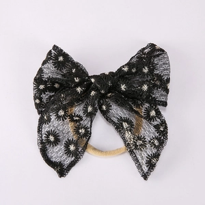 Détail de broderie de marguerites blanches sur nœud en dentelle noire avec bandeau bébé