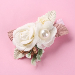 Detail of fabric rose flower hair clip with pearl bead and pink ribbon wrapped edge