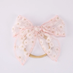 Détail du bandeau en dentelle rose avec broderie marguerite et ruban en nylon élastique