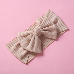 Dettaglio della fascia per neonata a coste beige con grande fiocco su sfondo rosa