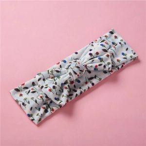 Détail du bandeau bébé en maille à fleurs avec motif baies et nœud décoratif doux