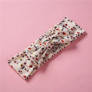 Détail du bandeau bébé à fleurs avec un grand nœud sur un fond rose doux