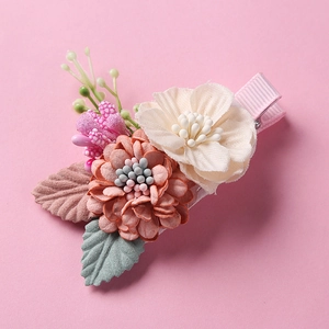 Close-up of pink and cream fabric flowers with green leaves and berries on hair clip