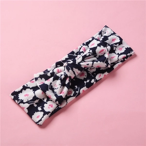Gros plan du bandeau floral pour bébé avec grand nœud sur un fond rose tendre