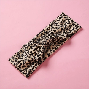 Détail du bandeau élastique en tricot pour bébé avec motif floral beige et grand nœud