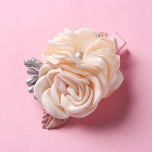 Detailed view of cream fabric flower hair clip with white pearl and silver glitter berries