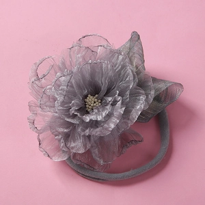 Détail d'un bandeau bébé à fleur en maille grise avec nylon souple et perles centrales