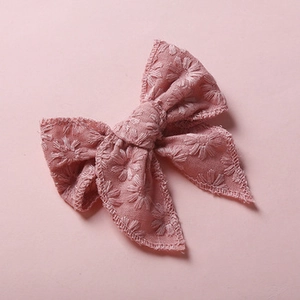 Detail of pink fabric hair bow with delicate daisy embroidery and soft textile texture