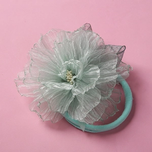 Détail d'un bandeau fleur en résille vert menthe avec élastique doux pour bébés