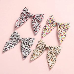 Close-up of four floral bow hair clips with embroidery on a soft pink background