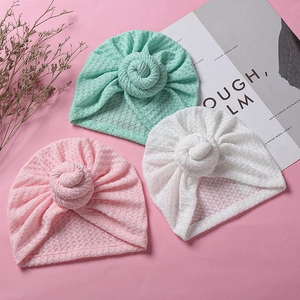 Detail von Baby-Waffelstrickmützen in Rosa, Minzgrün und Weiß mit Donut-Knoten