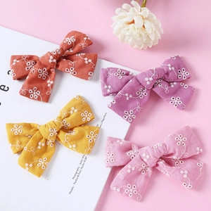 Detail showing embroidered daisy floral patterns on four colorful cotton linen hair bows