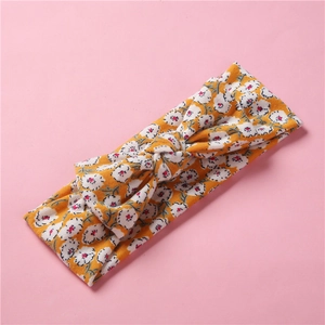Détail du bandeau bébé en tricot jaune à fleurs avec nœud élastique et motifs roses