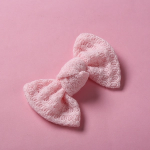 Gros plan d'une barrette à cheveux nœud rose tricoté montrant la texture du coton