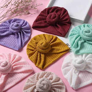 Details der Waffelstrick-Struktur von bunten Baby-Turban-Mützen mit Donut-Knoten