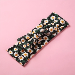 Détail d'un bandeau pour bébé avec motif de marguerites sur tissu vert foncé et nœud
