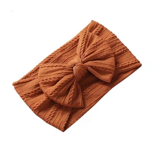 Bandeau bébé en maille torsadée avec grand nœud jaune moutarde sur fond blanc