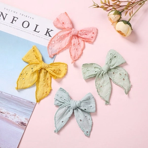 Detailed macro view of four colored linen hair bows with delicate floral embroidery