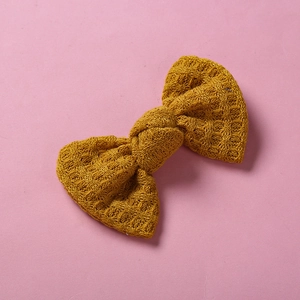 Gros plan détaillé d'un nœud à cheveux en tricot jaune moutarde avec texture gaufrée