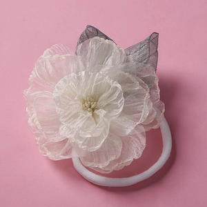 Détail d'un bandeau pour bébé en nylon souple avec fleur en organza 3D et feuilles en mesh