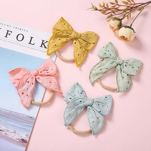 Detailed close-up of four-color embroidered daisy bow headbands with elastic nylon bands