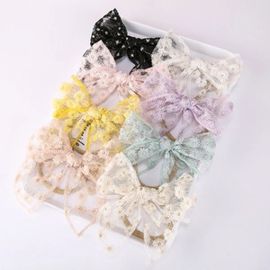 Close-up of seven assorted colors of lace daisy embroidered bow headbands on tray