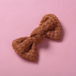 Gros plan d'une pince à cheveux nœud tricoté marron caramel avec texture en laine