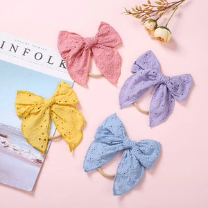 Detailed view of four colorful embroidered daisy bow headbands on a pink background