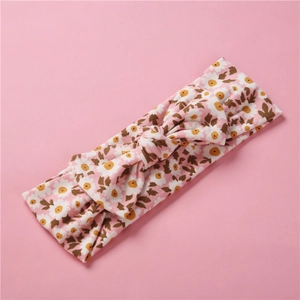 Détail d'un bandeau bébé souple avec motif marguerite rose et nœud décoratif